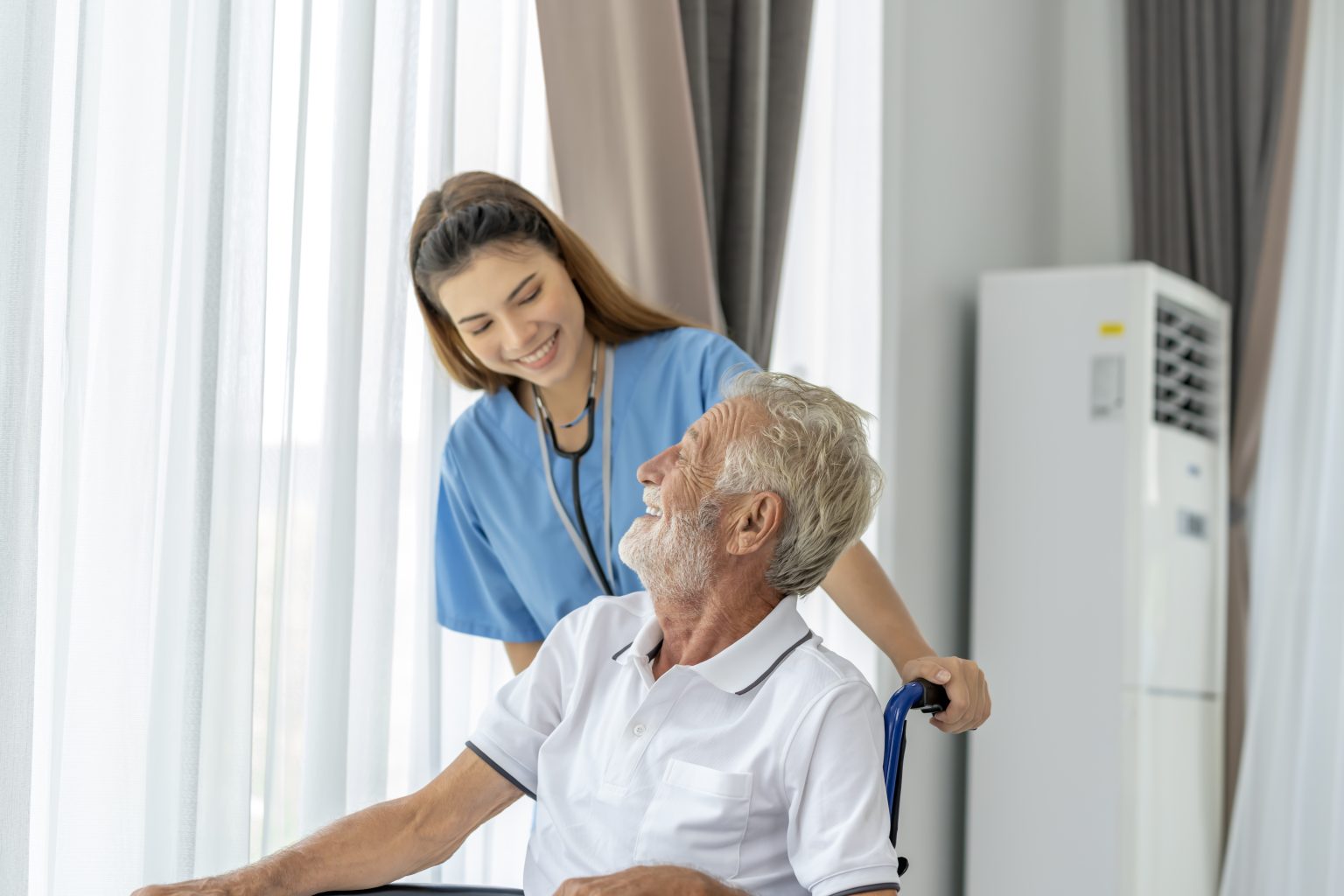 Nurse sharing a smile with an older patient in a wheelchair