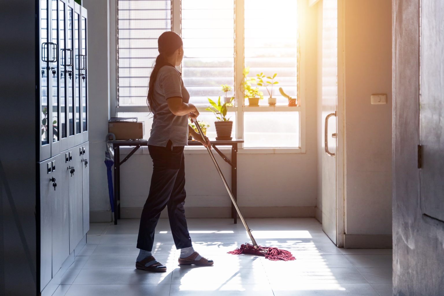 Woman using a mop to clean a hallway
