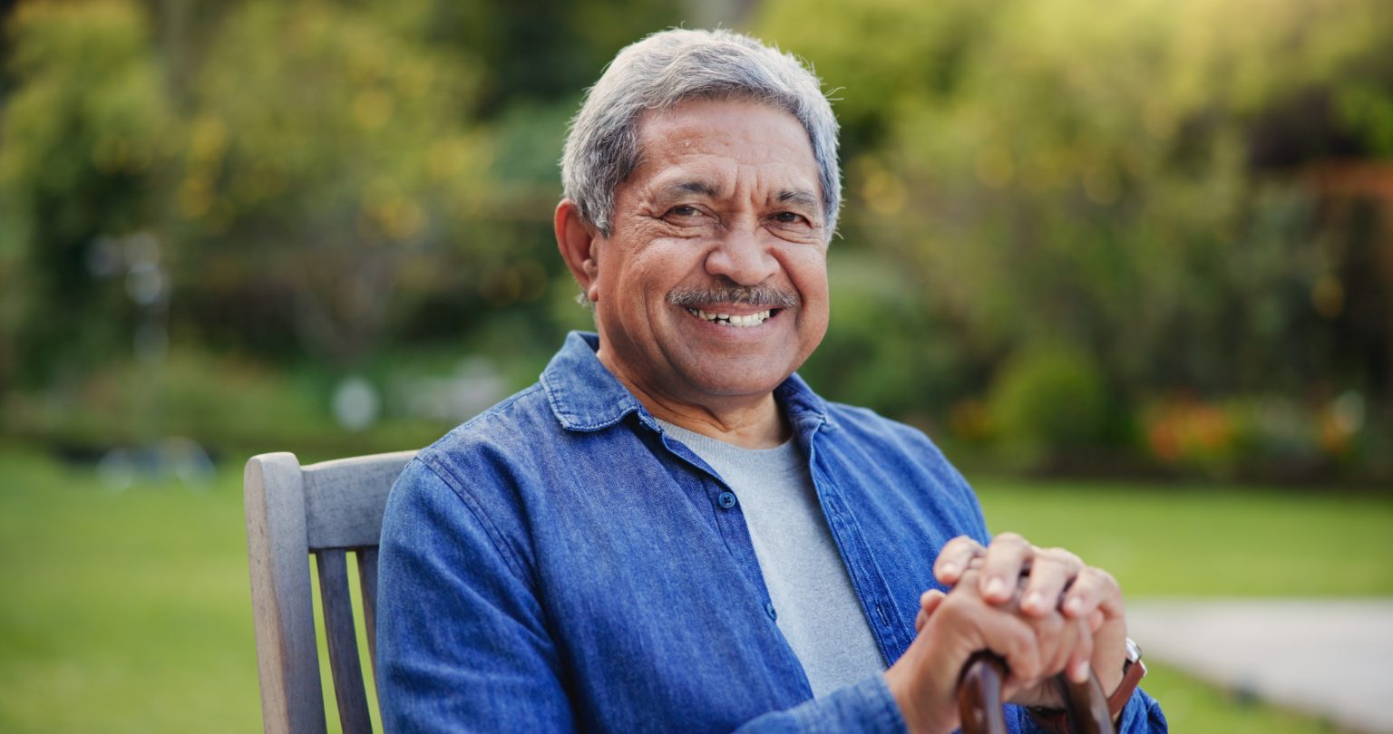Man smiling, sitting down on wooden chair
